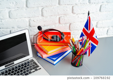 Laptop and flag of UK on desk. English language learning concept Laptop and flag of UK on desk. English language learning concept 109768192