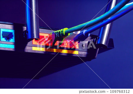 Cables plugged in a Wi-Fi router on dark background Cables plugged in a Wi-Fi router on dark background 109768312