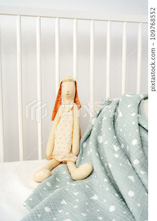 Wooden white baby crib and toy rabbit close up Wooden white baby crib and toy rabbit close up 109768552