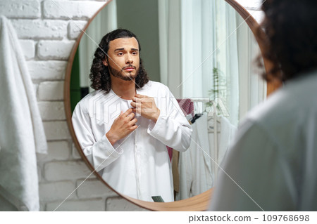 Young Arab man getting ready and looking at the mirror in the bathroom 109768698