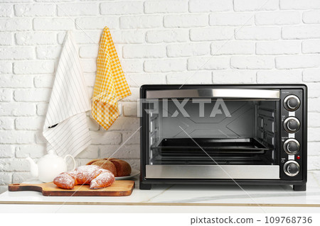 Modern mini electric oven with freshly baked croissants in kitchen Modern mini electric oven with freshly baked croissants in kitchen 109768736