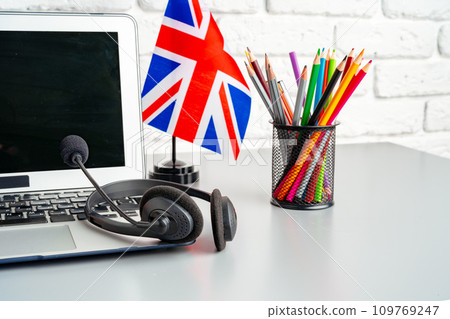 Laptop and flag of UK on desk. English language learning concept Laptop and flag of UK on desk. English language learning concept 109769247