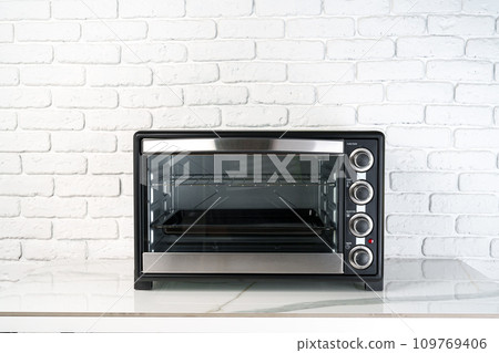 Mini electric oven against white brick wall in the kitchen 109769406