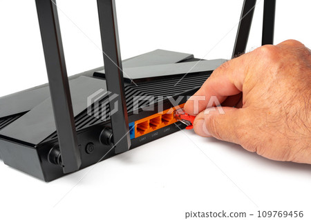 Man's hand plugging internet cable into wifi router Man's hand plugging internet cable into wifi router 109769456