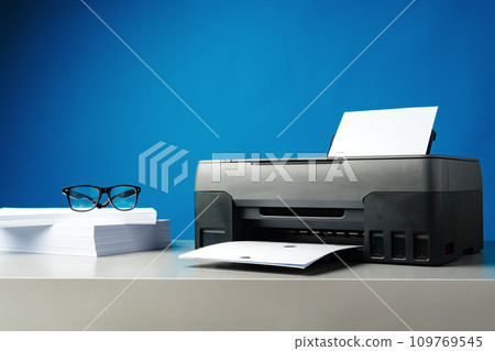 Laser printer on desk against blue background. 109769545