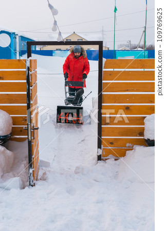 A man clear snow from backyard with snow blower. Winter season and snow blower equipment A man clear snow from backyard with snow blower. Winter season and snow blower equipment 109769625