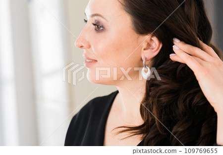 Close-up woman wearing beautiful luxury earrings copy space. Handmade jewellery and accessories. 109769655