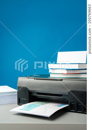 Laser printer on desk against blue background. Laser printer on desk against blue background. 109769663