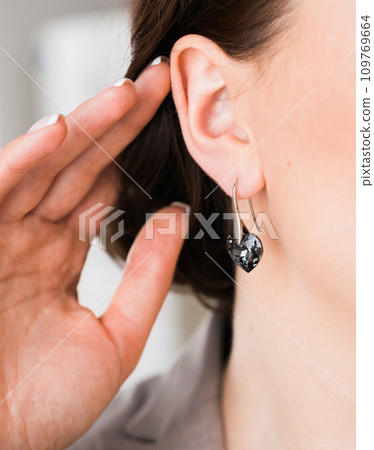 Close-up woman wearing beautiful luxury earrings. Handmade jewellery and accessories. Close-up woman wearing beautiful luxury earrings. Handmade jewellery and accessories. 109769664
