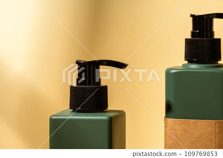 Dark green plastic bottles for skincare cosmetics on yellow background Dark green plastic bottles for skincare cosmetics on yellow background 109769853
