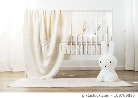 Baby wooden crib and toy rabbit in nursery room 109769886