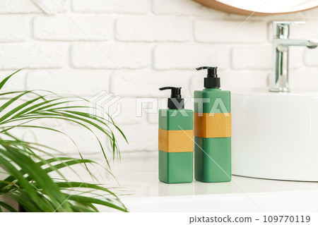Soap and cream dispenser jars near the sink in a bathroom Soap and cream dispenser jars near the sink in a bathroom 109770119