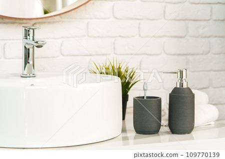 Bathroom interior with circle shaped mirror in wooden frame and white sink Bathroom interior with circle shaped mirror in wooden frame and white sink 109770139