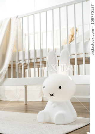 Baby wooden crib and toy rabbit in nursery room 109770187