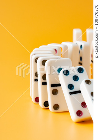 Row of domino tiles on yellow studio background 109770270