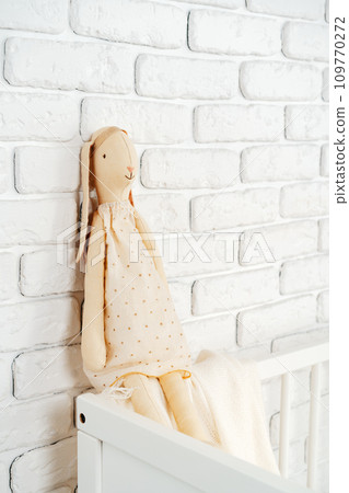 Soft rabbit toy at white children's wooden bed 109770272