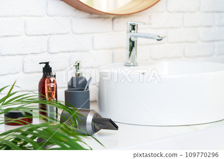 Bathroom interior with circle shaped mirror in wooden frame and white sink 109770296