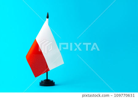 Small flag of Poland on flagpole on blue background 109770631