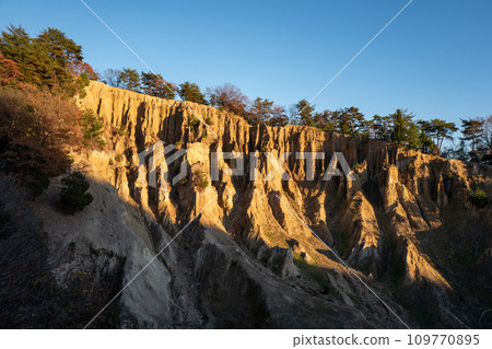 [Awa City, Tokushima Prefecture] Earthen pillars of Awa illuminated by the setting sun [Hatodake] 109770895