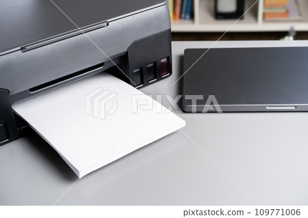 Printer and laptop on grey table in office 109771006