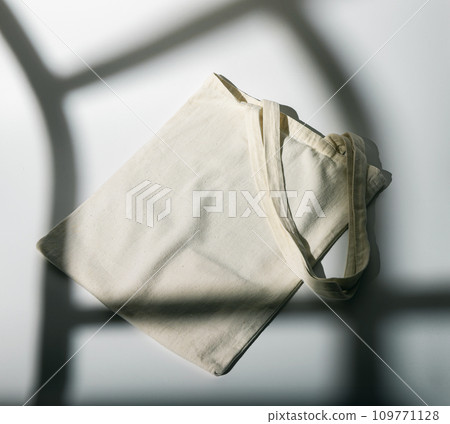Eco natural textile tote bag. Recycled reusable organic shopper mockup, sunny light from window Eco natural textile tote bag. Recycled reusable organic shopper mockup, sunny light from window 109771128