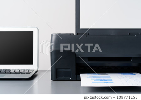 Printer and laptop on grey table in office 109771153