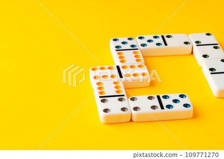 Domino tiles on yellow background studio shot Domino tiles on yellow background studio shot 109771270