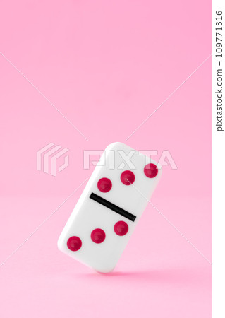 Domino piece on pink background close up 109771316
