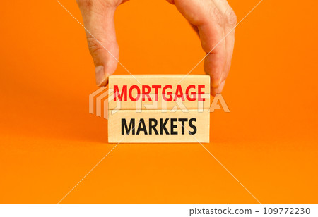 Mortgage markets symbol. Concept words Mortgage markets on beautiful wooden blocks. Beautiful orange table orange background. Businessman hand. Business mortgage markets concept. Copy space. 109772230