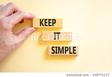 Keep it simple symbol. Concept word Keep it simple on beautiful wooden block. Businessman hand. Beautiful white table white background. Business motivational keep it simple concept. Copy space. 109772257