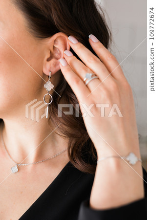 Detail of young woman wearing beautiful luxury earring and bracelet. Handmade jewellery and accessories Detail of young woman wearing beautiful luxury earring and bracelet. Handmade jewellery and accessories 109772674