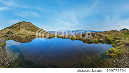 Small picturesque lake with clouds reflections at the  Strymba Mount. Beautiful autumn day in Carpathian Mountains near Kolochava village, Transcarpathia, Ukraine. 109772704
