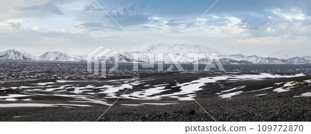 Iceland highlands autumn ultrawide view. Lava fields of volcanic sand in foreground. Hrauneyjalon lake and volkanic snow covered mountains in far. 109772870