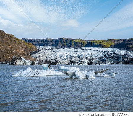 Solheimajokull picturesque glacier in southern Iceland. The tongue of this glacier slides from the volcano Katla. Beautiful glacial lake lagoon with blocks of ice and surrounding mountains. 109772884