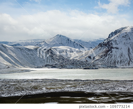 Season changing in southern Highlands of Iceland. Colorful Landmannalaugar mountains under snow cover in autumn. Frostastadavatn lake at the foot of the mountains. Season changing in southern Highlands of Iceland. Colorful Landmannalaugar mountains under snow cover in autumn. Frostastadavatn lake at the foot of the mountains. 109773214