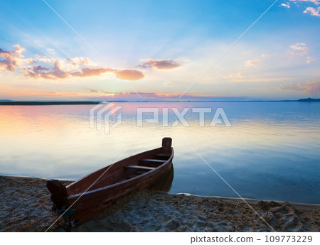 Sunset with boat near the summer lake shore Sunset with boat near the summer lake shore 109773229