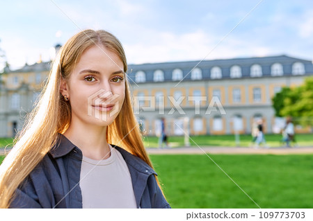 Headshot portrait of young teenage female looking at camera outdoor 109773703