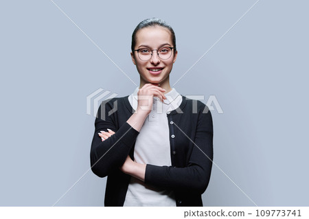 Portrait of smiling teenager girl on grey background 109773741