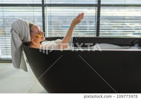 Spa relaxation. Young woman lying in bath with foam bubbles. Girl relaxing in bathroom at home. Pretty female spending morning in bathroom enjoying taking bath. Beauty treatment body skin care concept Spa relaxation. Young woman lying in bath with foam bubbles. Girl relaxing in bathroom at home. Pretty female spending morning in bathroom enjoying taking bath. Beauty treatment body skin care concept 109773978
