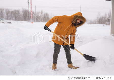 Man cleaning snow from sidewalk and using snow shovel. Winter season Man cleaning snow from sidewalk and using snow shovel. Winter season 109774955