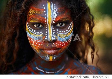 Portrait showcasing the rich heritage of Australian Aboriginal indigenous culture. Woman adorned with traditional patterns standing in wooded area with trees and foliage in background 109774970