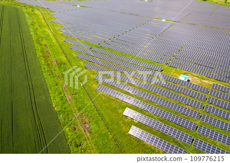 Aerial view of solar power plant on green field. Electric panels for producing clean ecologic energy. Aerial view of solar power plant on green field. Electric panels for producing clean ecologic energy. 109776215