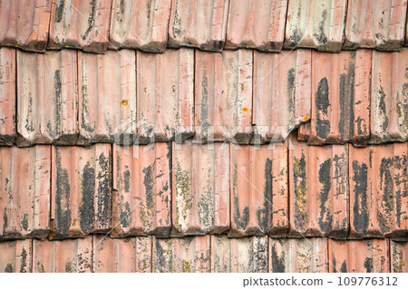 Closeup surface of old weathered ceramic tiles covering building roof Closeup surface of old weathered ceramic tiles covering building roof 109776312