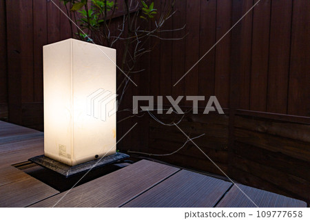 古色古香的傍晚庭院、日式燈光和門廊上的樹木、木牆（東京千代田區） 109777658