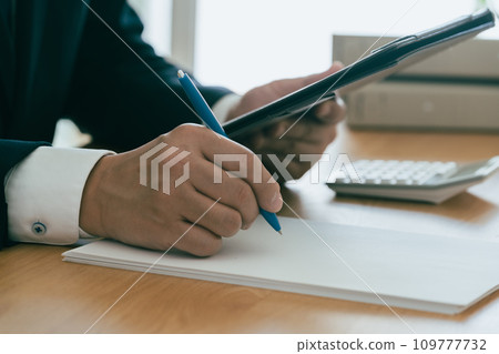Hand of a man in a suit taking notes on information Hand of a man in a suit taking notes on information 109777732