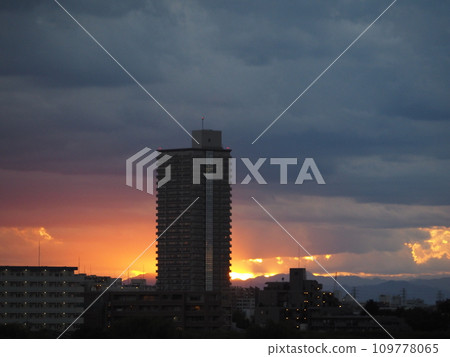 A skyscraper apartment towering against the backdrop of an orange sunset A skyscraper apartment towering against the backdrop of an orange sunset 109778065