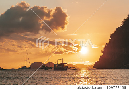 Traditional philippine boats bangka at sunset time. Beautiful sunset with silhouettes of philippine boats in El Nido, Palawan island, Philippines. Orange sky sunset paradise beach. 109778466
