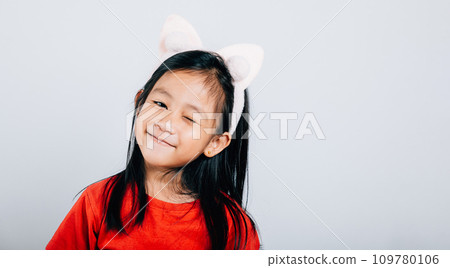 A joyful Asian kid girl in a red t-shirt beams with happiness her open mouth revealing a big smile and confidence. Isolated portrait of a cheerful child on a white background. A joyful Asian kid girl in a red t-shirt beams with happiness her open mouth revealing a big smile and confidence. Isolated portrait of a cheerful child on a white background. 109780106