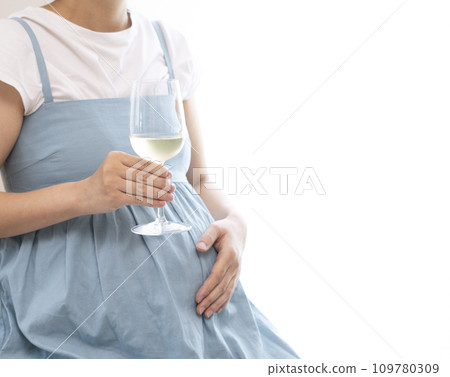 Pregnant woman holding a wine glass filled with wine 109780309