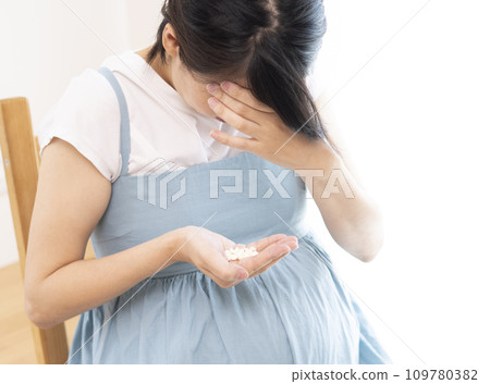 Image of a woman holding her head and holding medicine Image of a woman holding her head and holding medicine 109780382